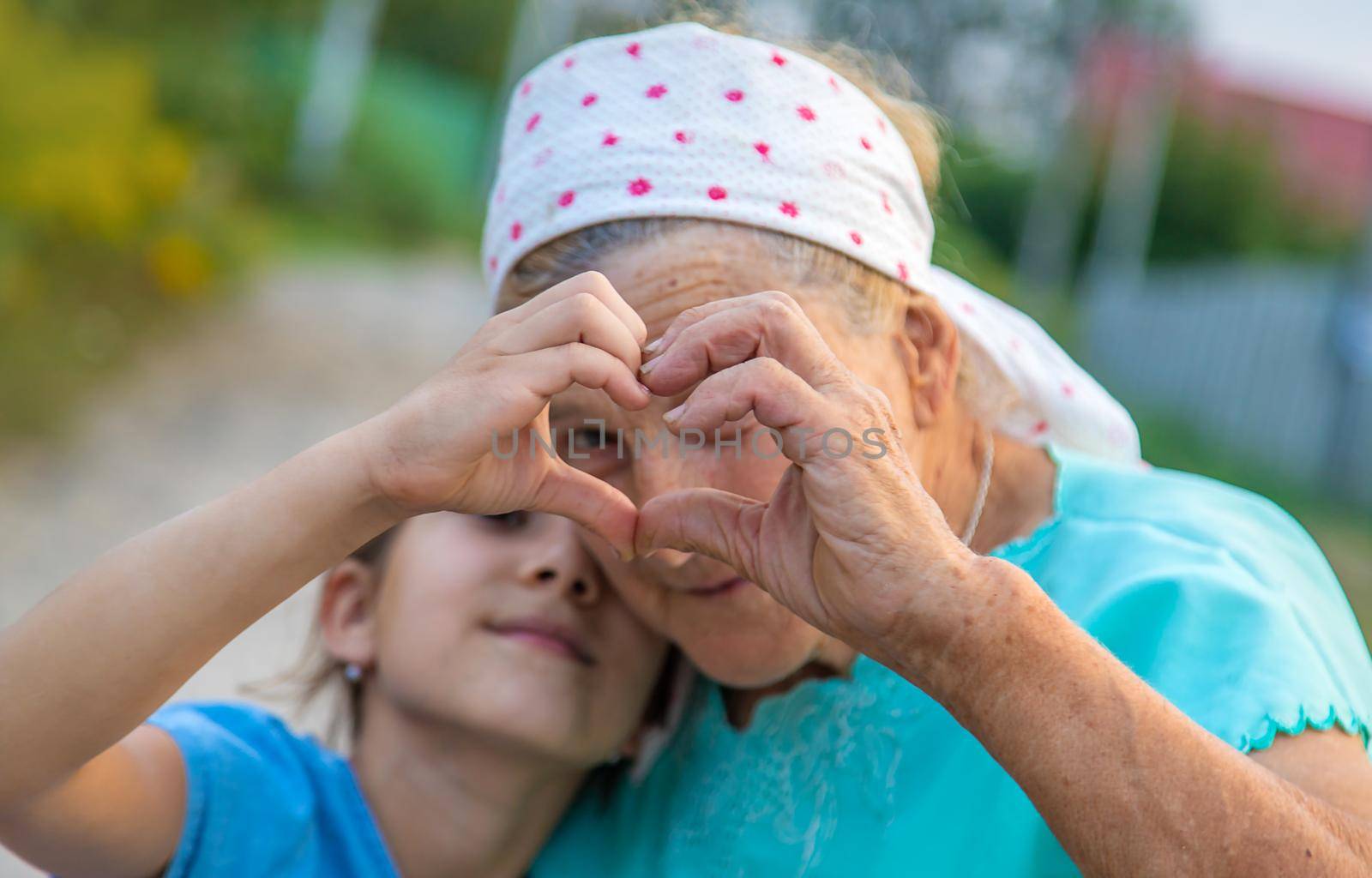 Grandmother and granddaughter make a heart with their hands. Selective focus. People.