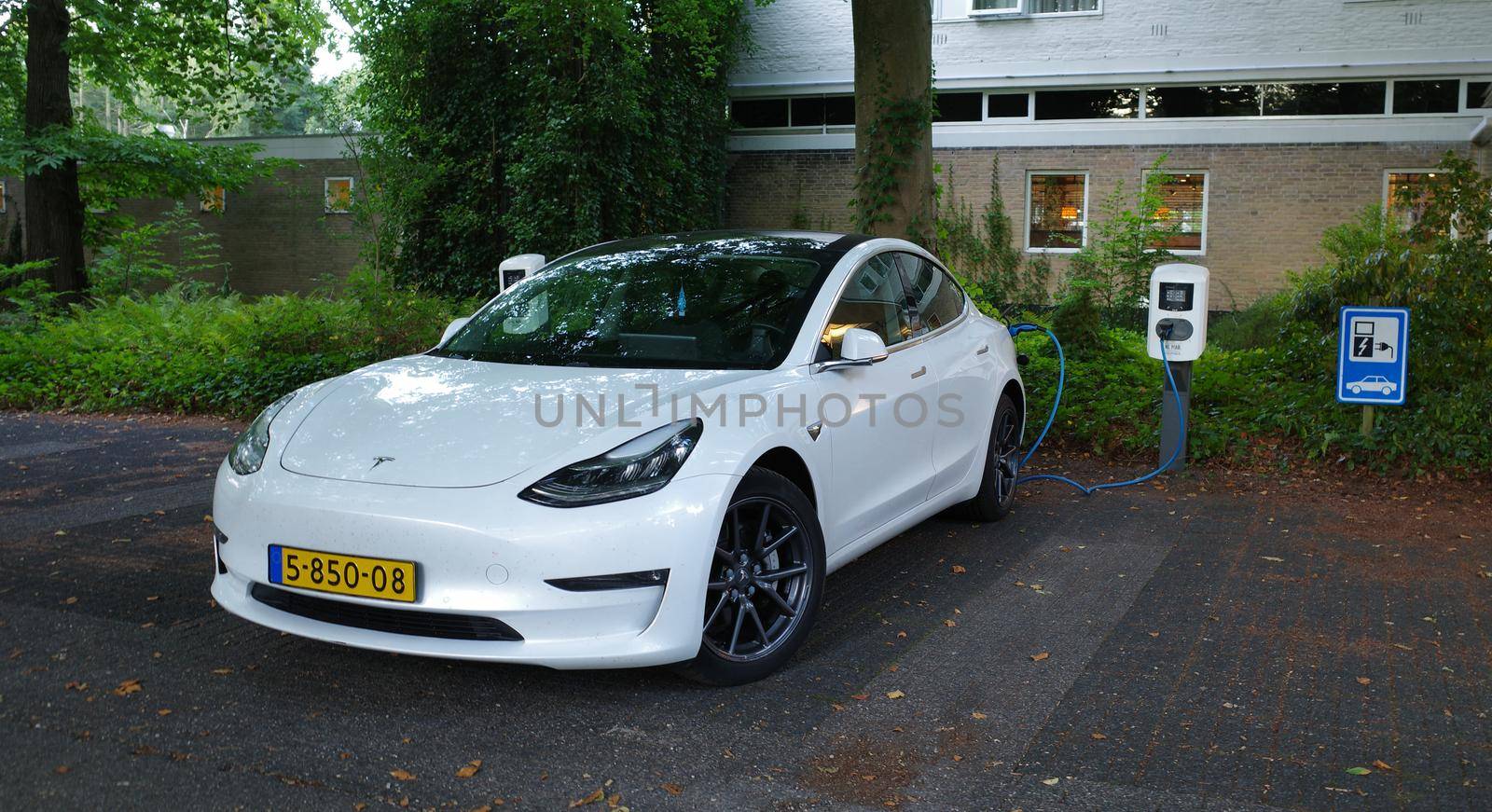 Amersfoort, Netherlands - August 28 2022 A white Testa Model 3 being charged. This is a compact executive sedan that is battery powered. It's at the moment the world's top selling electric car