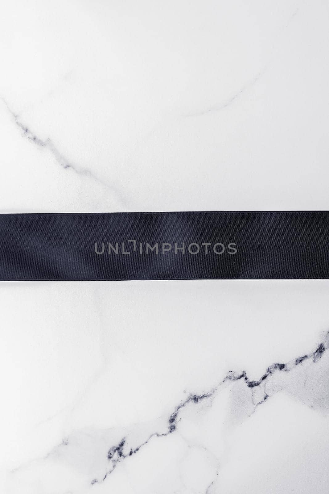 Black silk ribbon and bow on marble background, flatlay by Anneleven