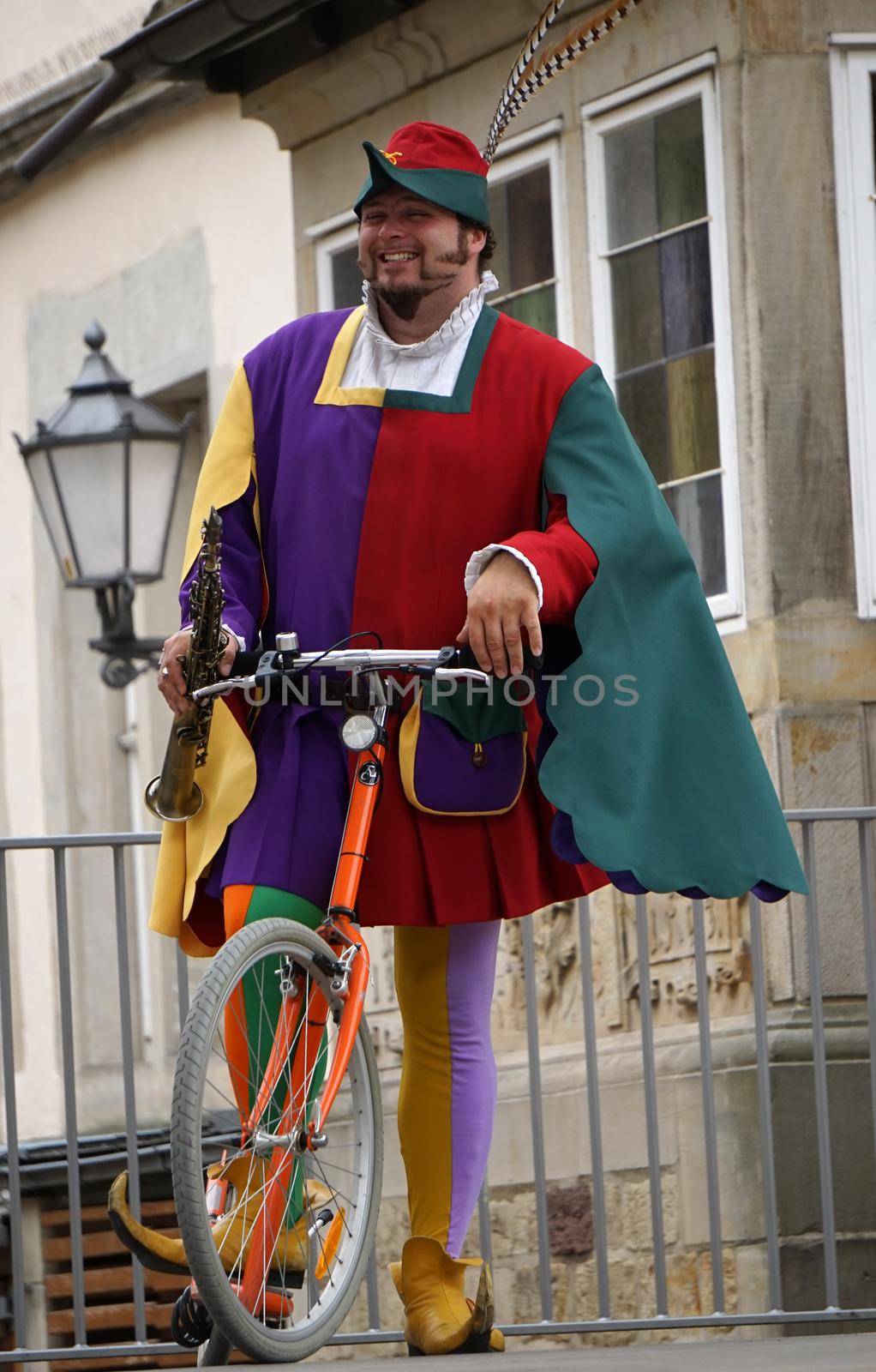 Hamelin, Germany - July 16 2017 The Pied Piper of Hamelin, dressed in multicolored clothes, rides a scooter with a clarinet in his hand through Hamelin for the tourists