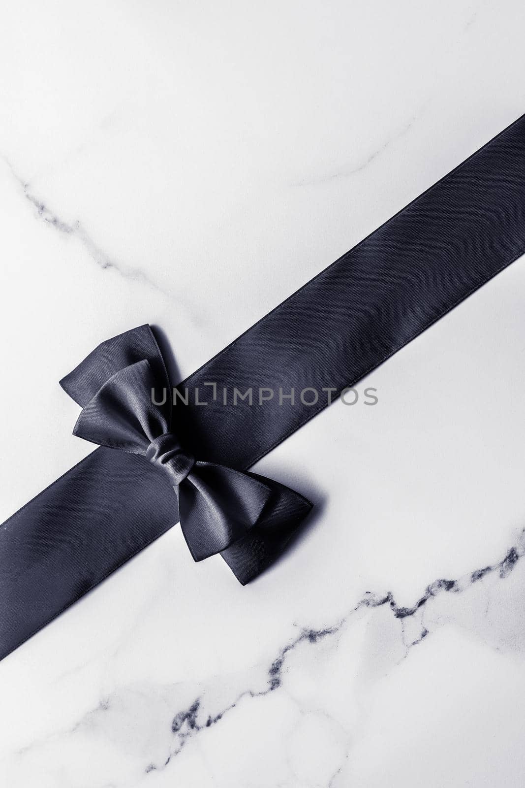 Holiday gift, decoration and sale promotion concept - Black silk ribbon and bow on marble background, flatlay