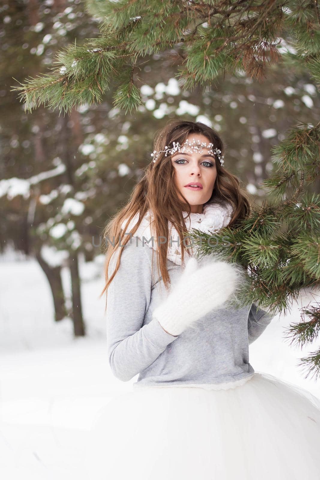 Beautiful bride in a white dress with a bouquet in a snow-covered winter forest. Portrait of the bride in nature.