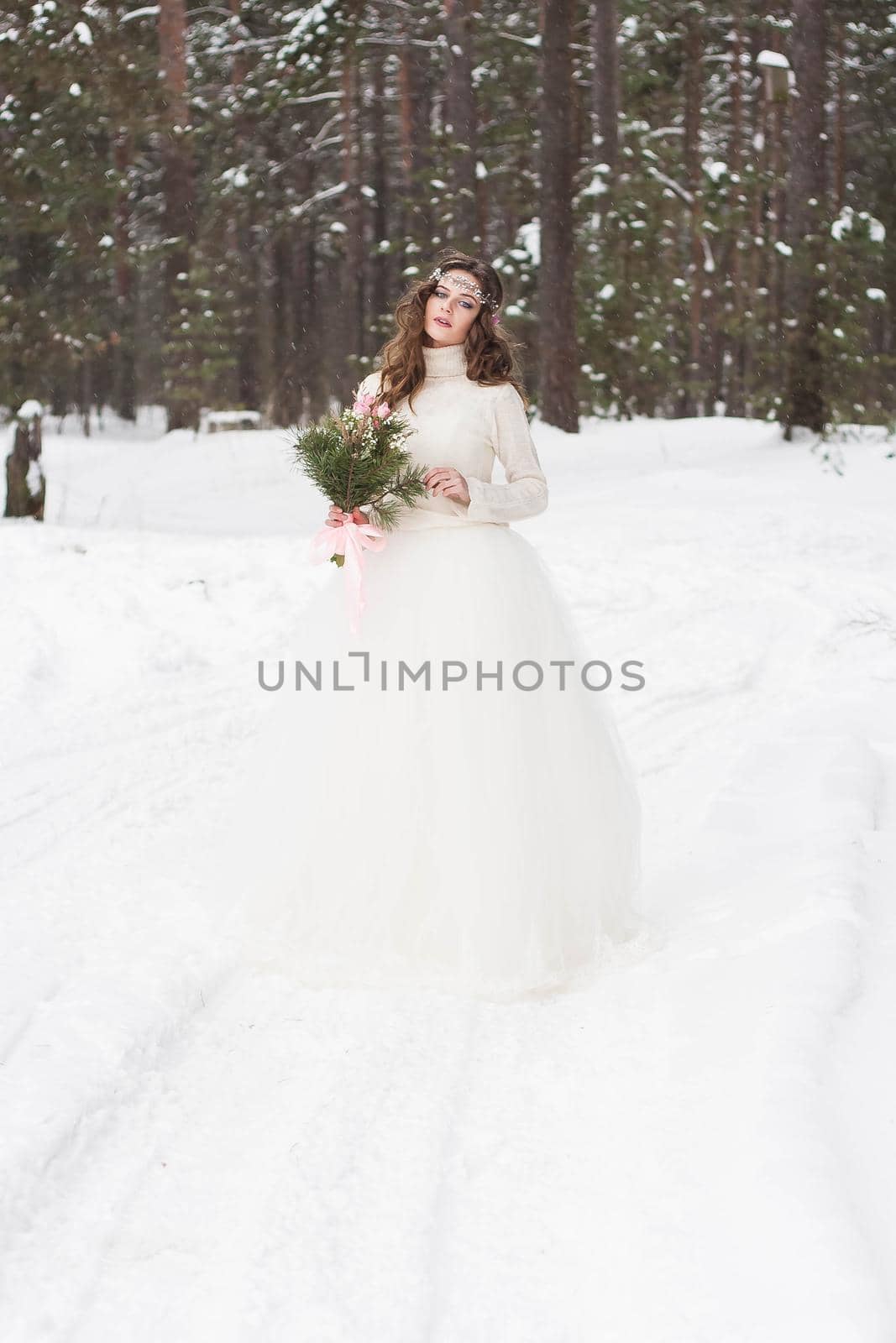 Beautiful bride in a white dress with a bouquet in a snow-covered winter forest. Portrait of the bride in nature by Annu1tochka