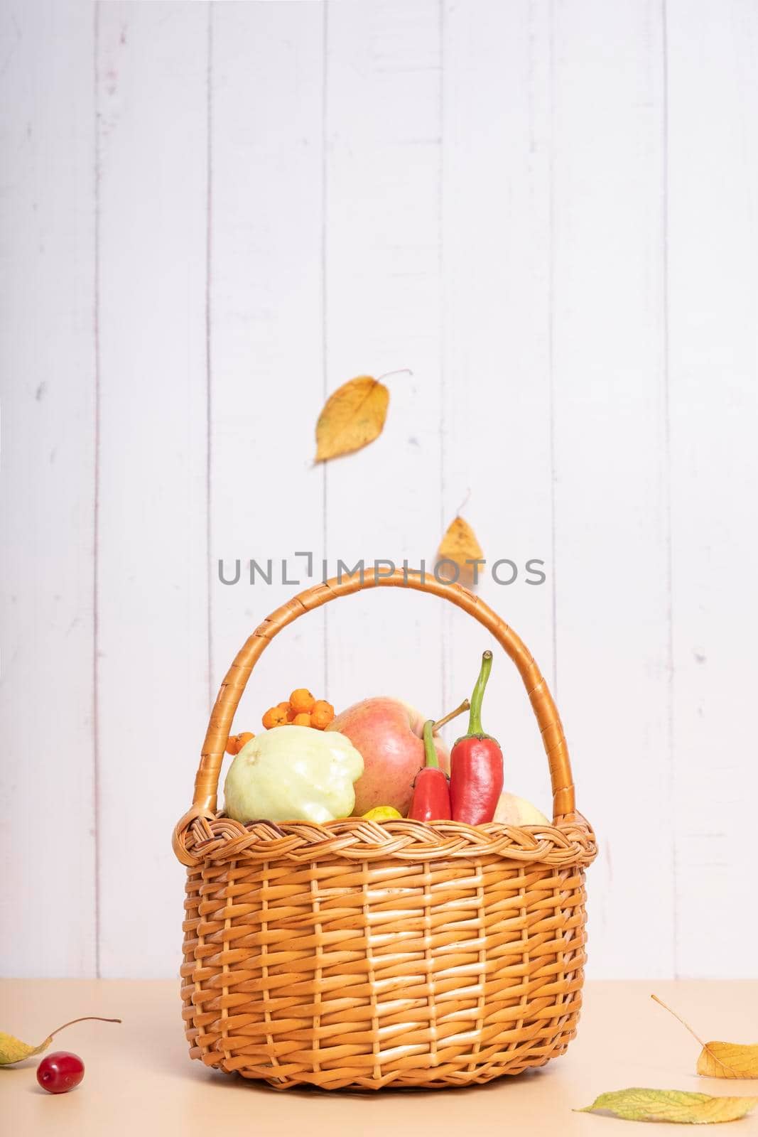 Autumn harvest basket with apples, zucchini and peppers on a wooden background. Vertical photo