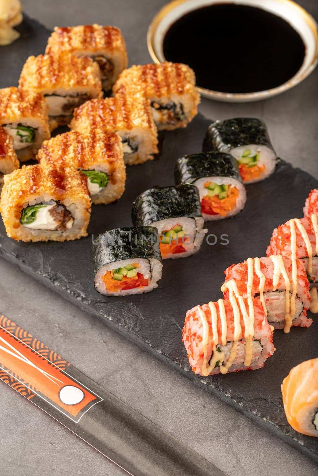 Sushi set of various products on a black stone plate. Blur background and selective focus by Sonat