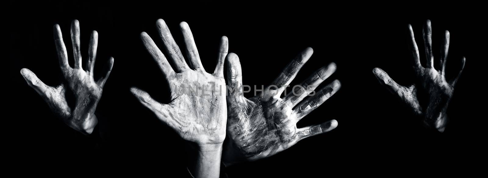 Close up shot of hands of children with some paint over it isolated over a black background, horizontal shot.