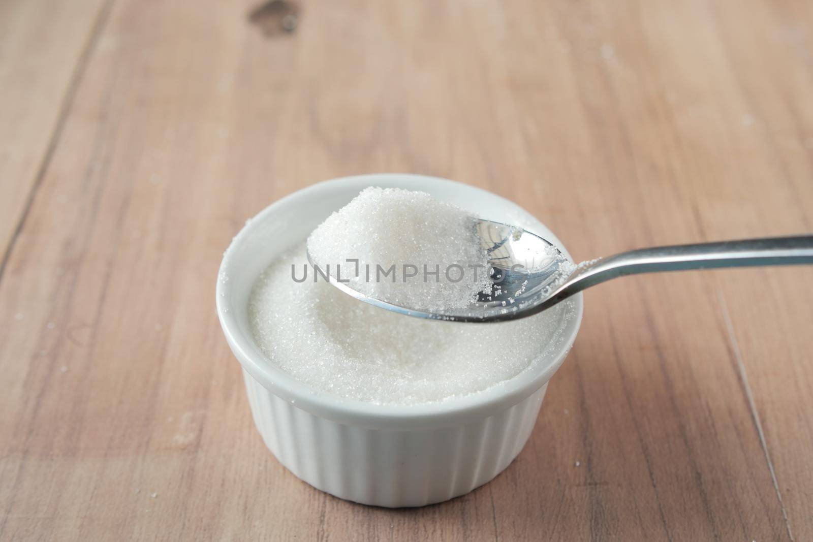white sugar and spoon in a container on black background