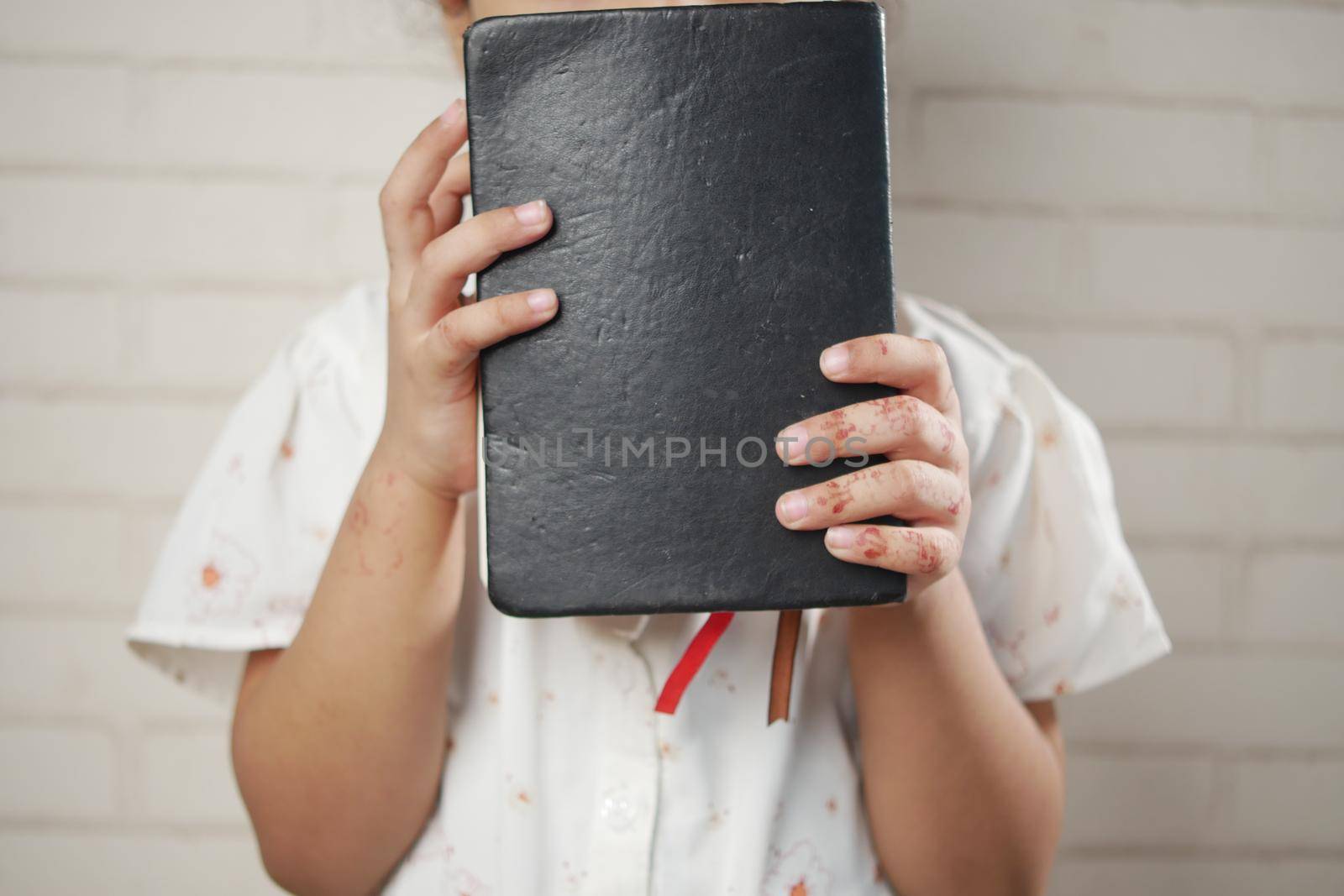 child girl holding many colorful notepad sited on chair .