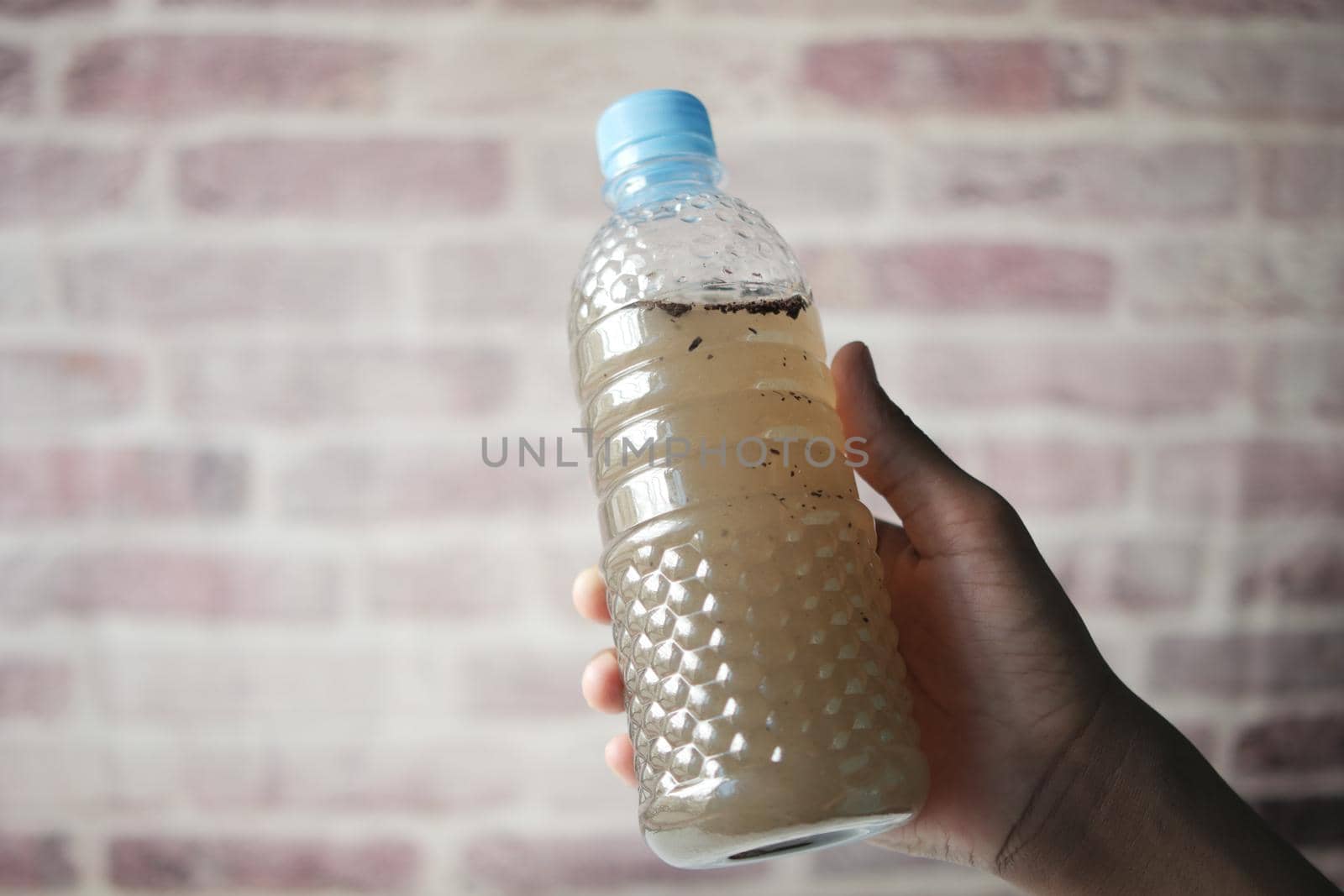 holding dirty bottle of water .