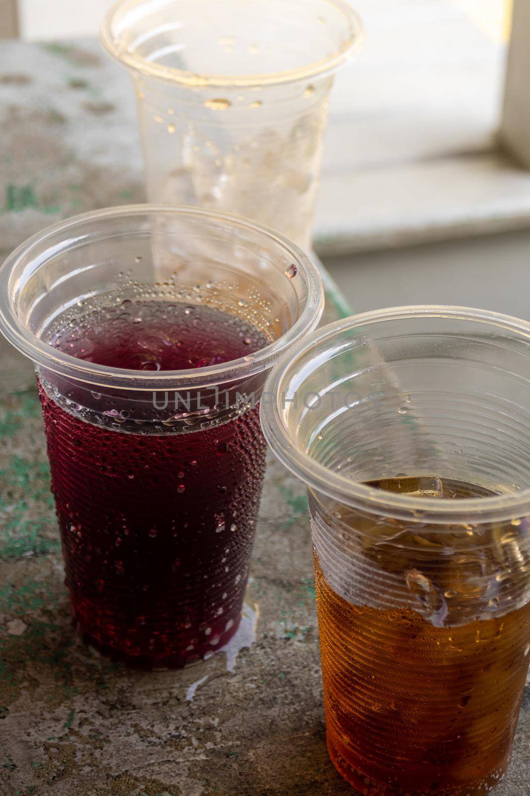 Soft drink and ice in the disposable plastic glasses by Satakorn