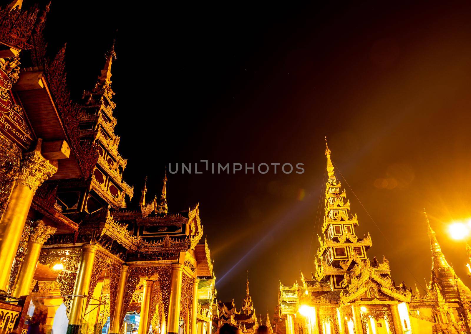 The golden pagodas and mondops are illuminated in the light of the night by Satakorn