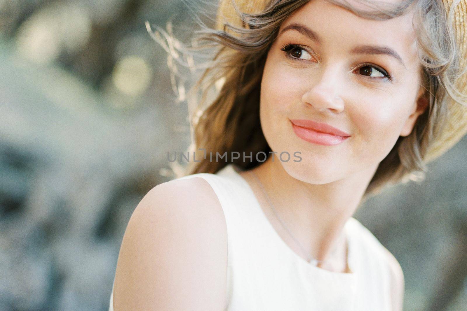 Smiling woman in a straw hat with her hair blowing in the wind. Portrait. High quality photo