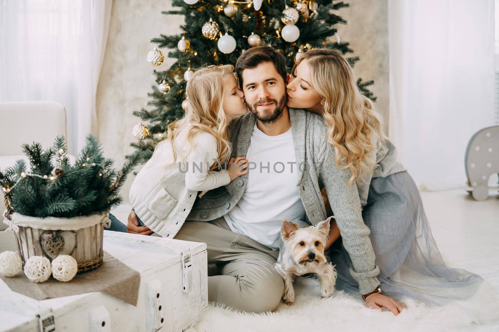 Happy family: mom, dad and pet. Family in a bright New Year's interior with a Christmas tree.