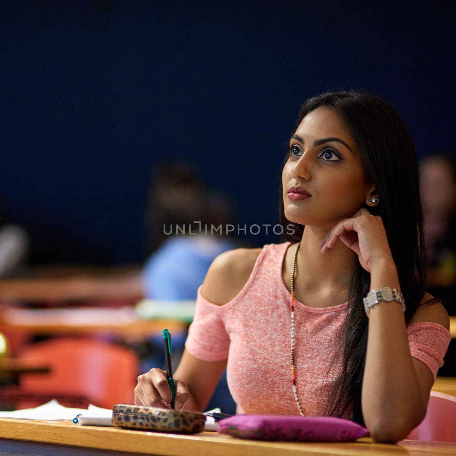 She takes her education seriously. a beautiful university student making notes while sitting in a lecture hall. by YuriArcurs