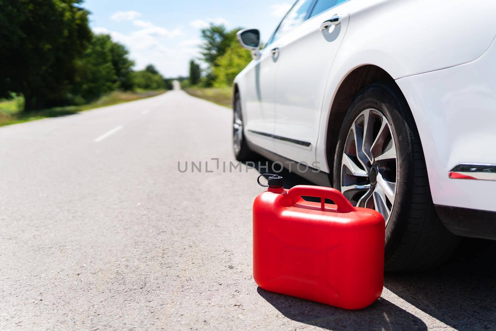 A car parked on the side of the road, an empty red canister. The driver is on the road. Help on the road. Fuel shortage - oil, diesel, gasoline
