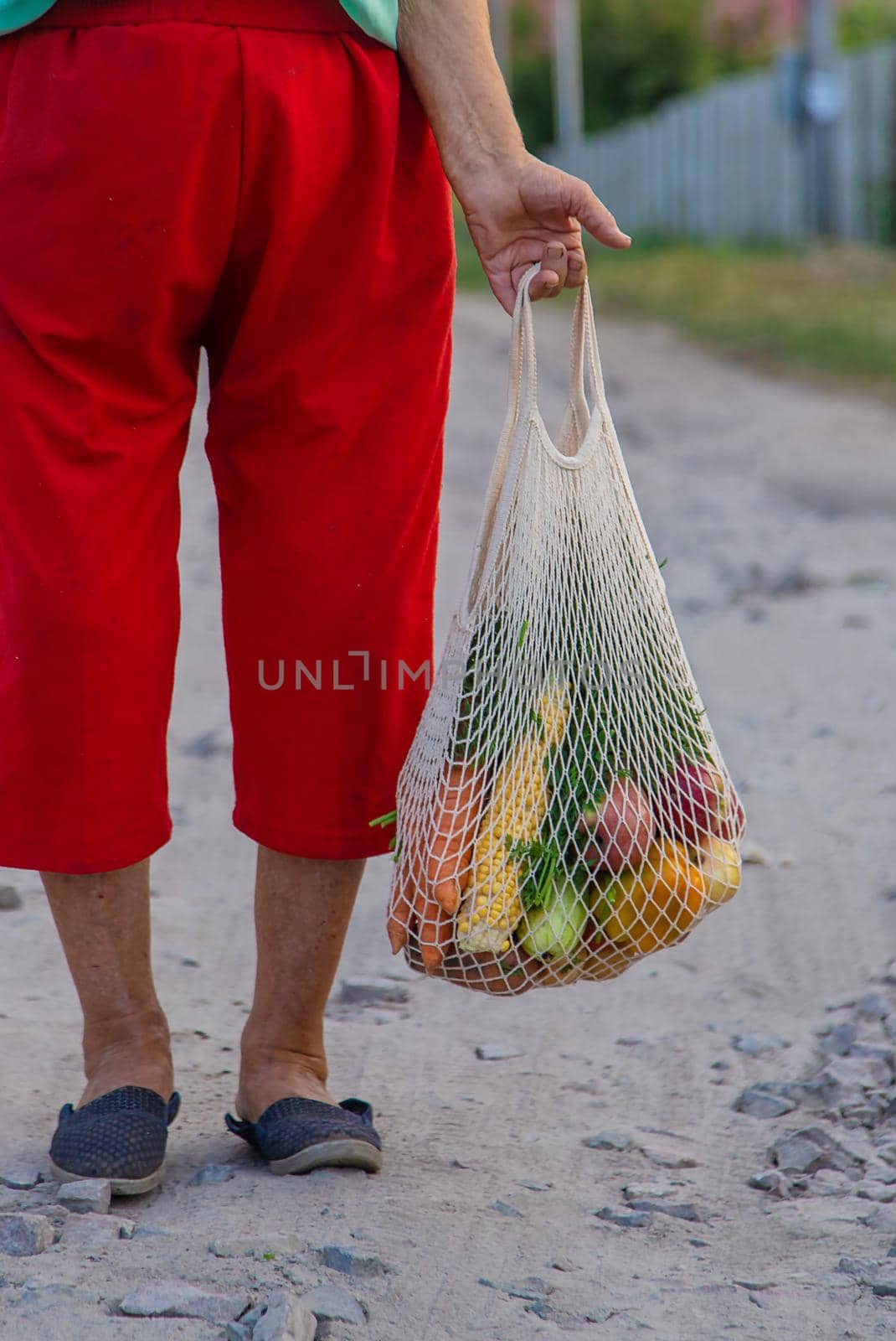 Grandmother carries vegetables in a shopping bag. Selective focus. by yanadjana