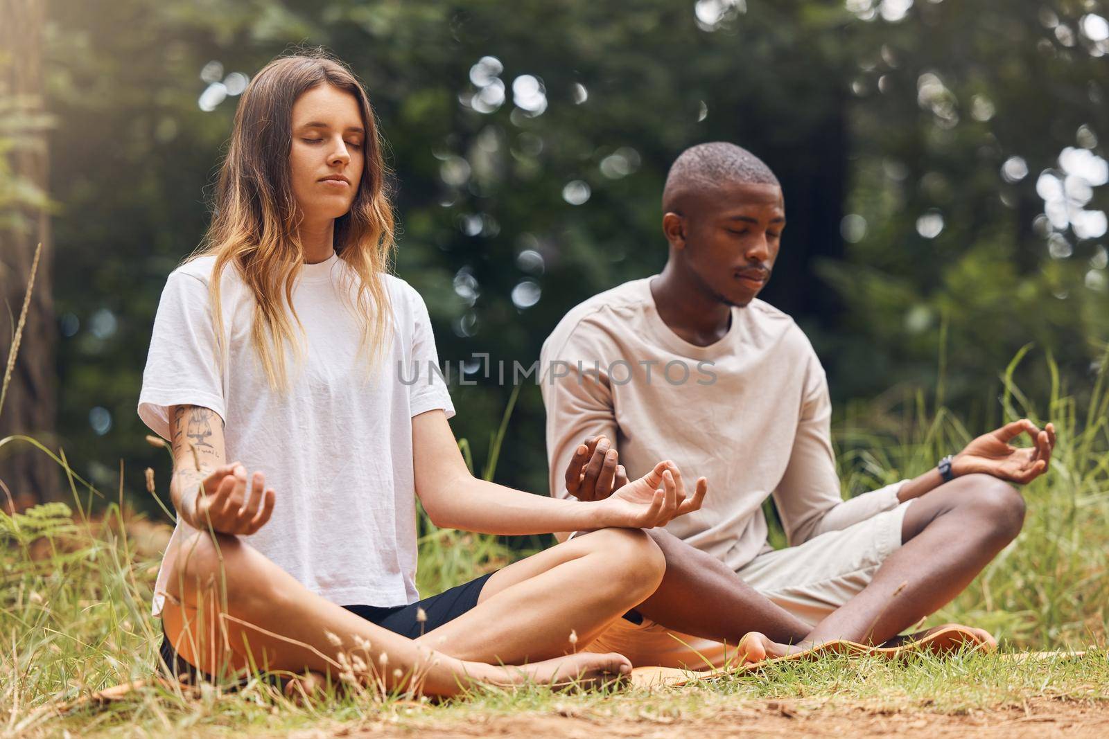 Yoga, interracial couple and meditation for zen and balance with black man and white woman sitting in lotus at a park in nature. Calm and content with holistic spiritual exercise and health training by YuriArcurs