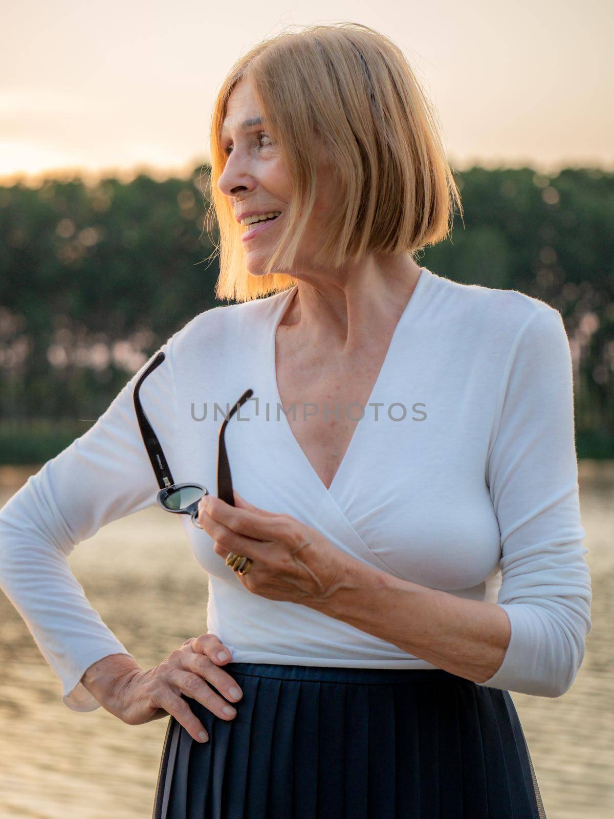 joyful senior fit elegant lady dressed white and blue wearing sunglasses enjoying nature in summer