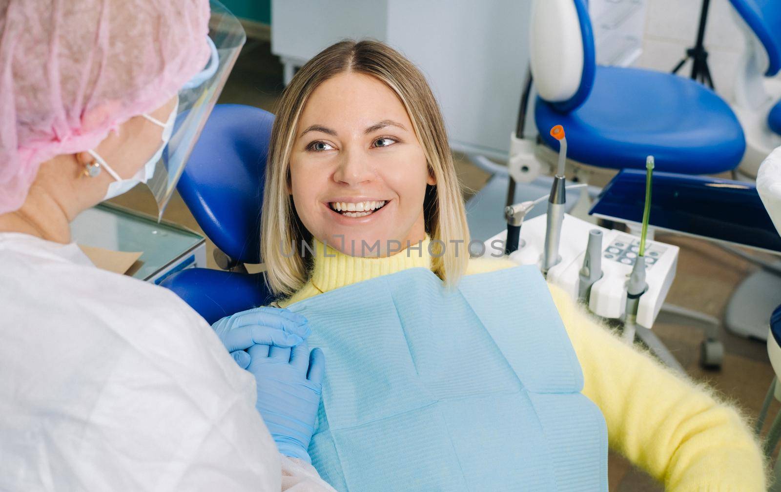 The girl smiles at the dentist and looks at her.