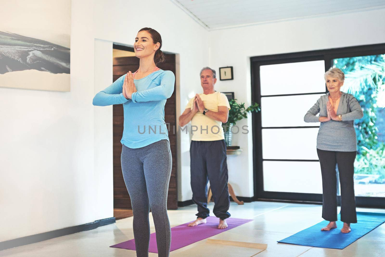 Happiness is lead by healthy habits. a yoga instructor guiding a senior couple in a yoga class. by YuriArcurs