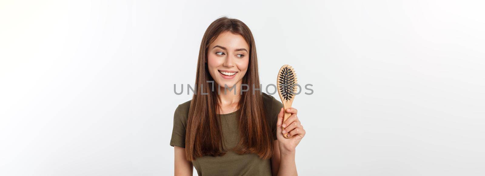 Happy young woman combing her long healthy hair on white background