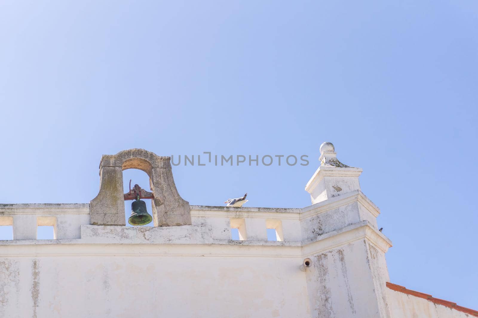 Bell on the roof of an old Portuguese Catholic church on a sunny day against the sky