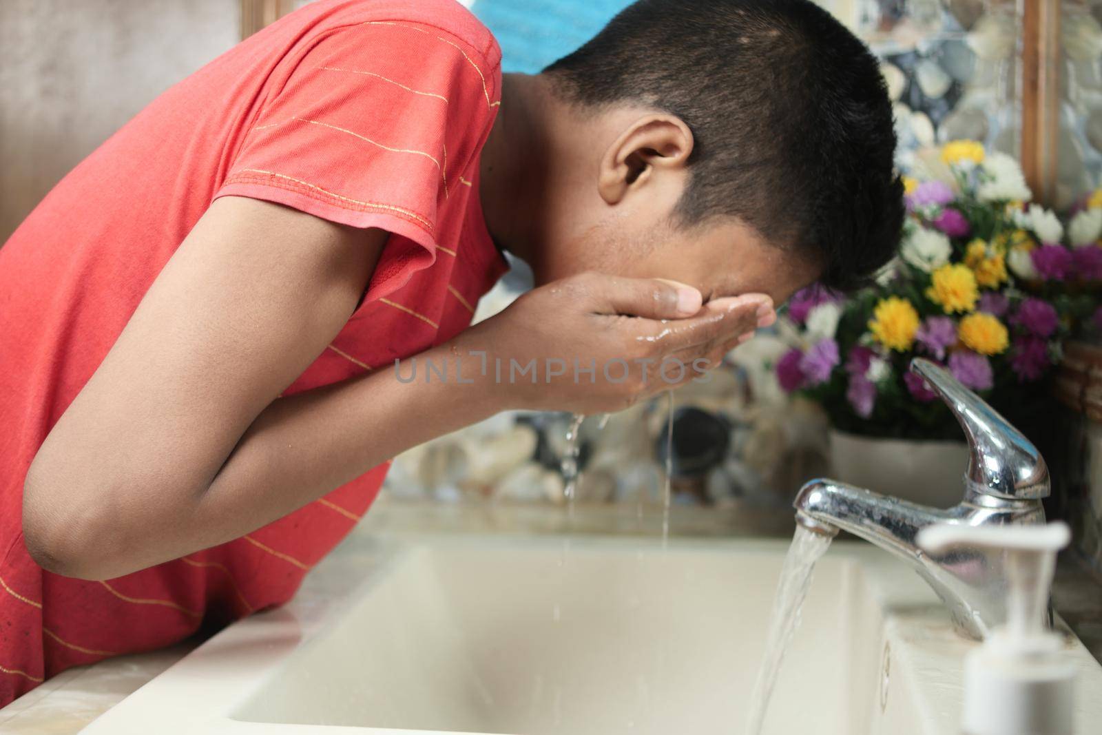 teenage boy cleaning face with a clean water