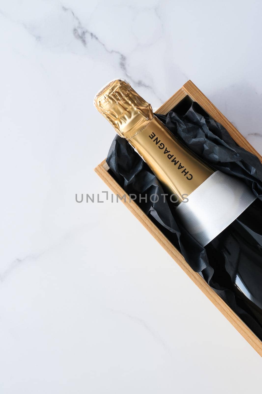 A champagne bottle and a gift box on marble by Anneleven