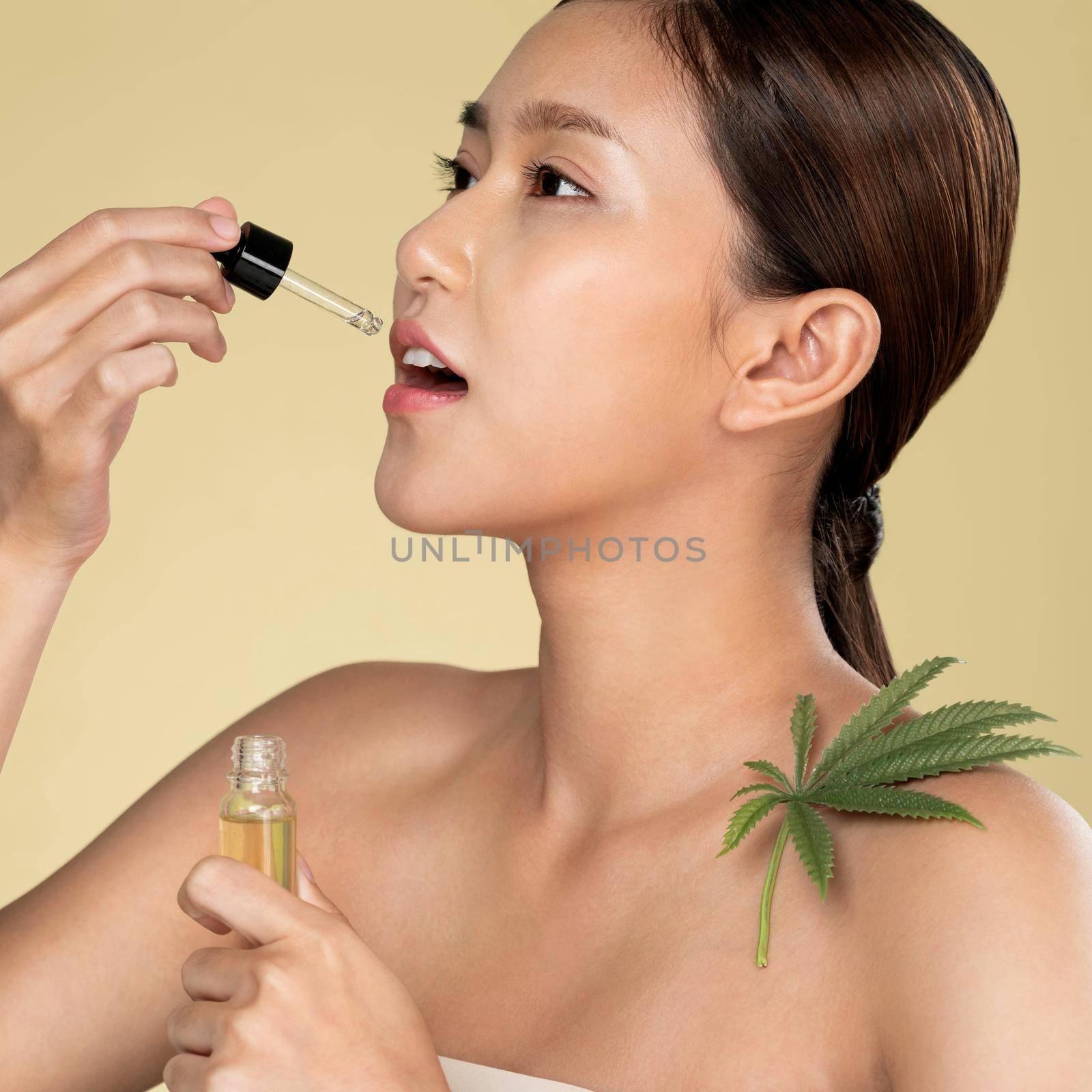 Closeup young ardent woman with healthy skin taking cbd oil with hemp leaf. by biancoblue