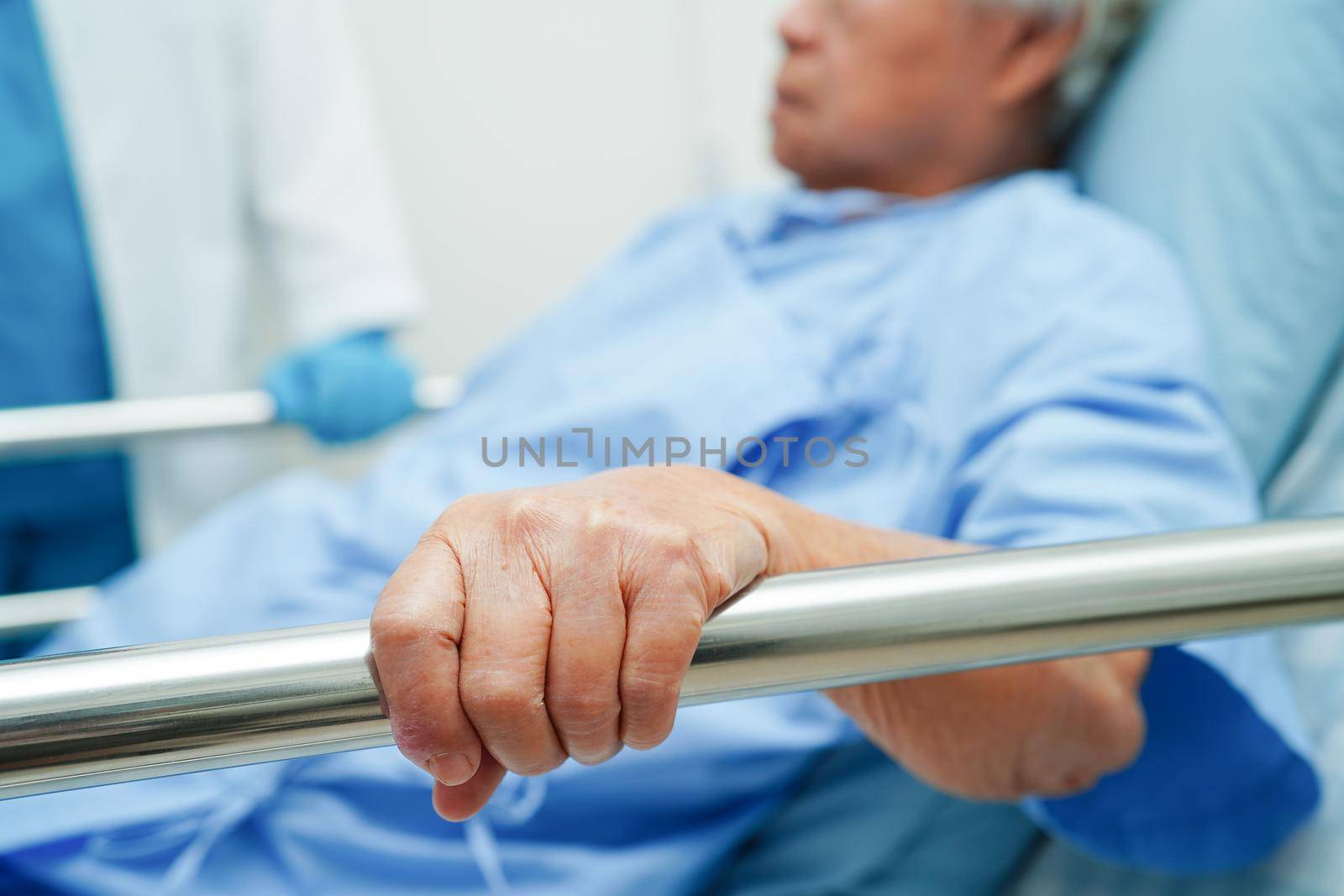 Asian elder senior woman patient holding bed rail while lie down with hope waiting her family in hospital.
