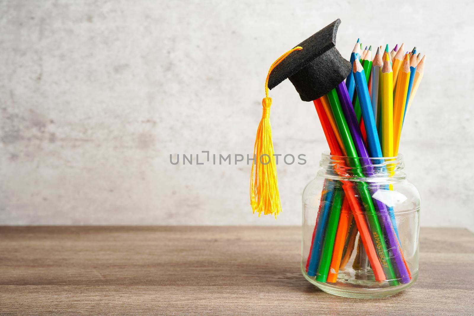 Graduation hat with colorful pencils on book with copy space, learning university education concept.