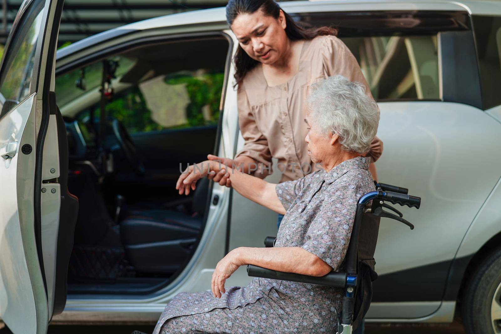 Caregiver help Asian elderly woman disability patient get in her car, medical concept.