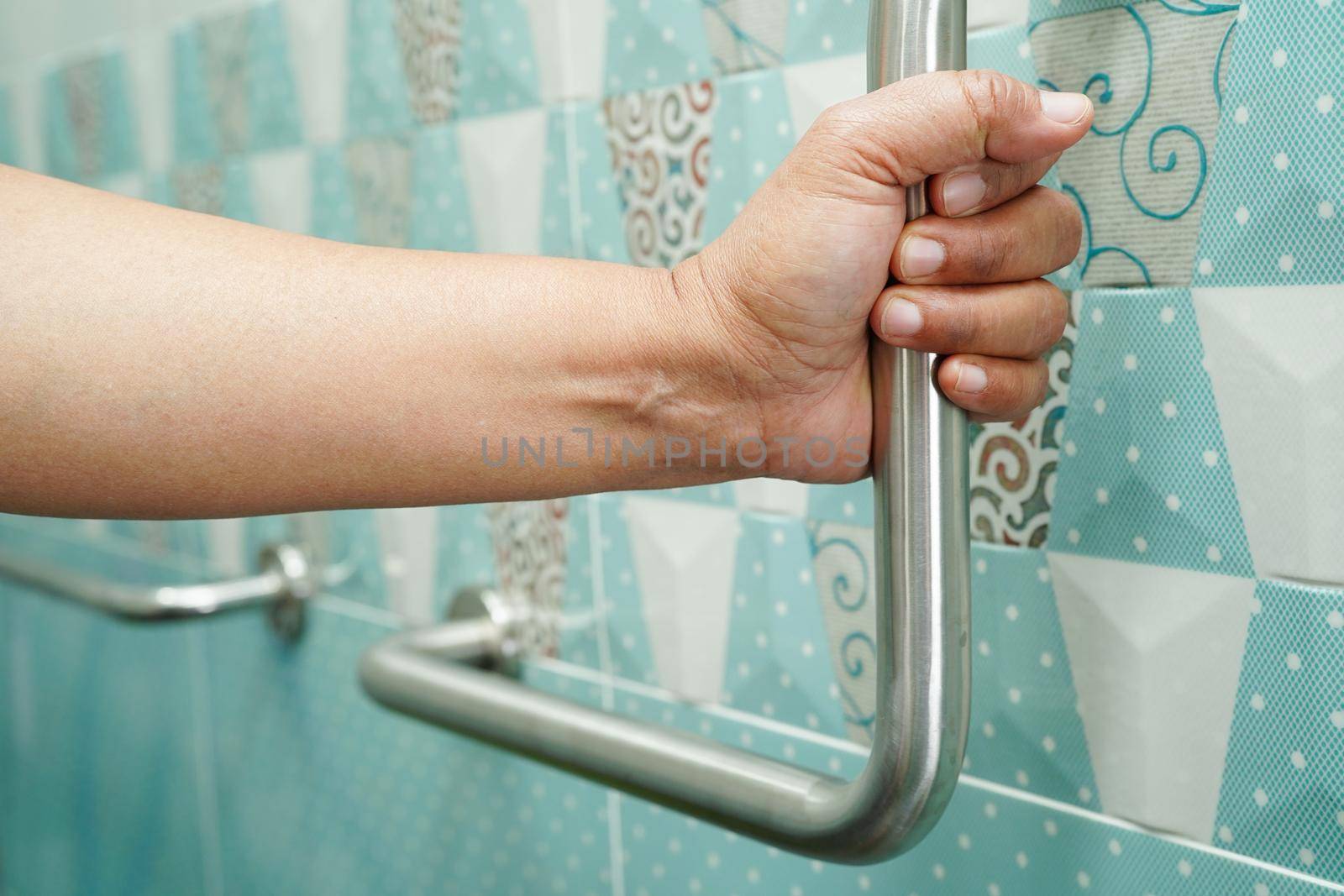 Asian woman patient use toilet support rail in bathroom, handrail safety grab bar, security in nursing hospital.