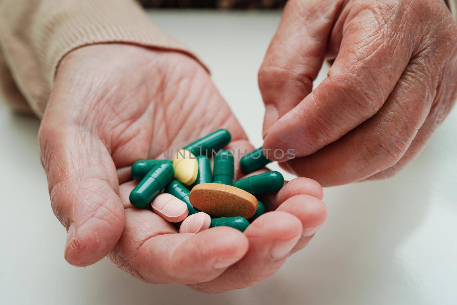 Asian elderly woman holding pill drug in hand, strong healthy medical concept. 