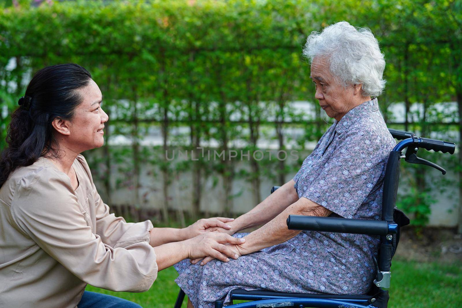 Caregiver help Asian elderly woman disability patient sitting on wheelchair in park, medical concept. by sweettomato