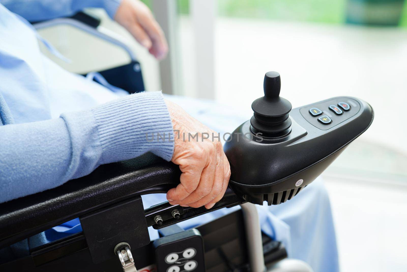 Asian elderly woman disability patient sitting on electric wheelchair in park, medical concept.
