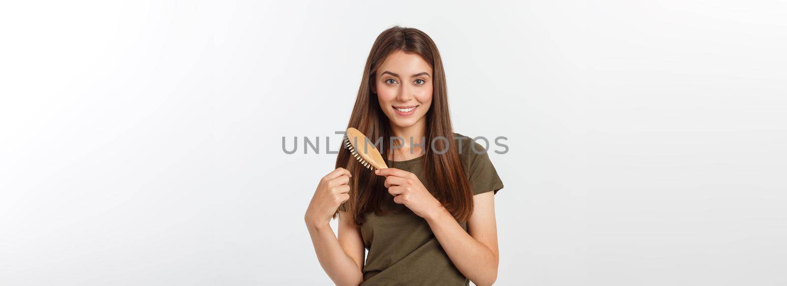 Happy young woman combing her long healthy hair on white background