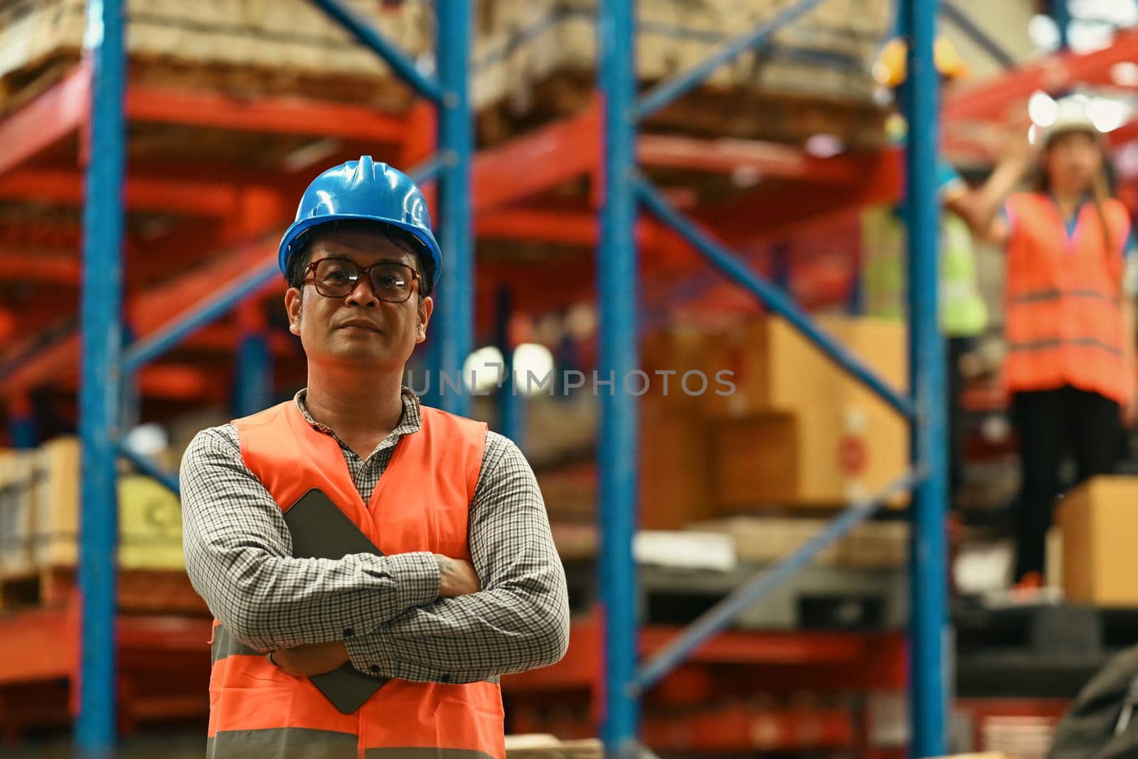 Portrait of mature male supervisor standing in warehouse with his arm crossed and looking at camera.