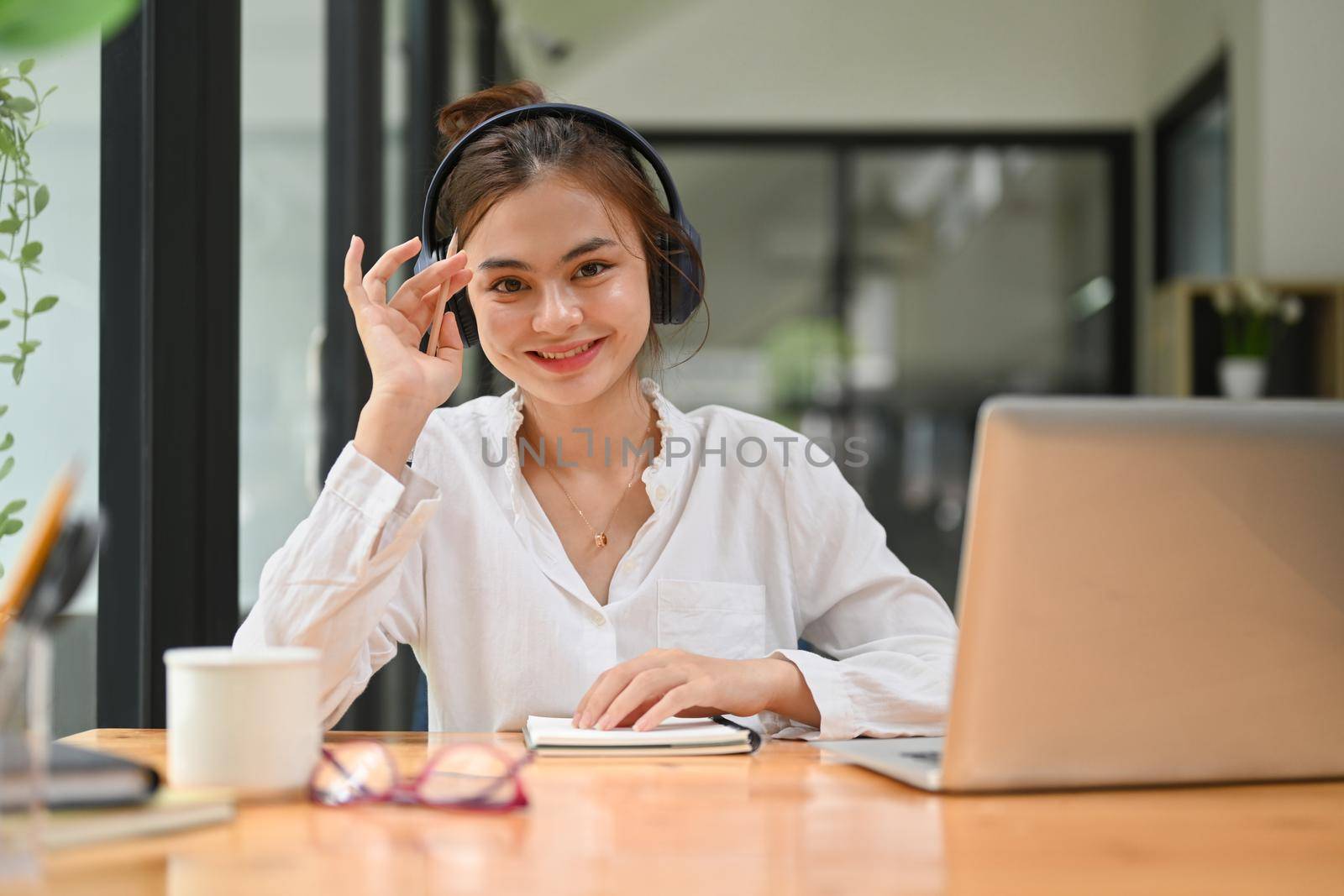 Happy young woman wearing wireless headphone having learning online at virtual class on laptop computer. E-learning education concept.