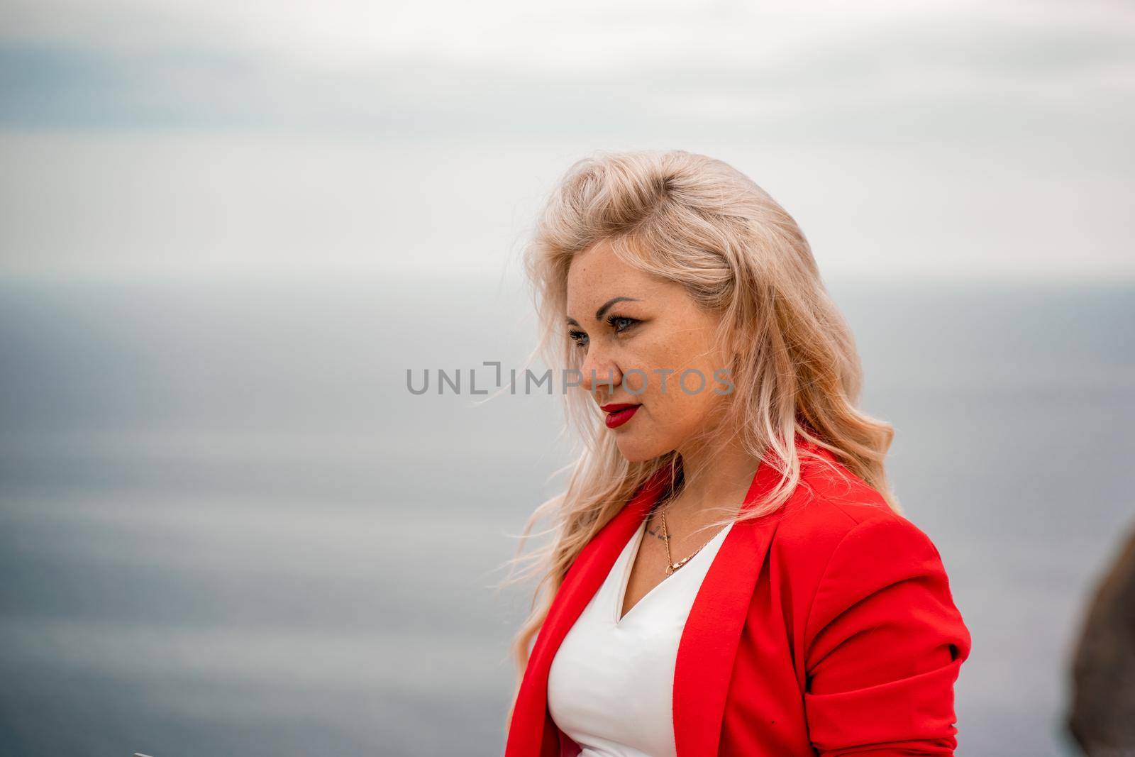 A woman is typing on a laptop keyboard on a terrace with a beautiful sea view. Close up of a woman's hands writing on a computer. Freelancing, digital nomad, travel and vacation concept