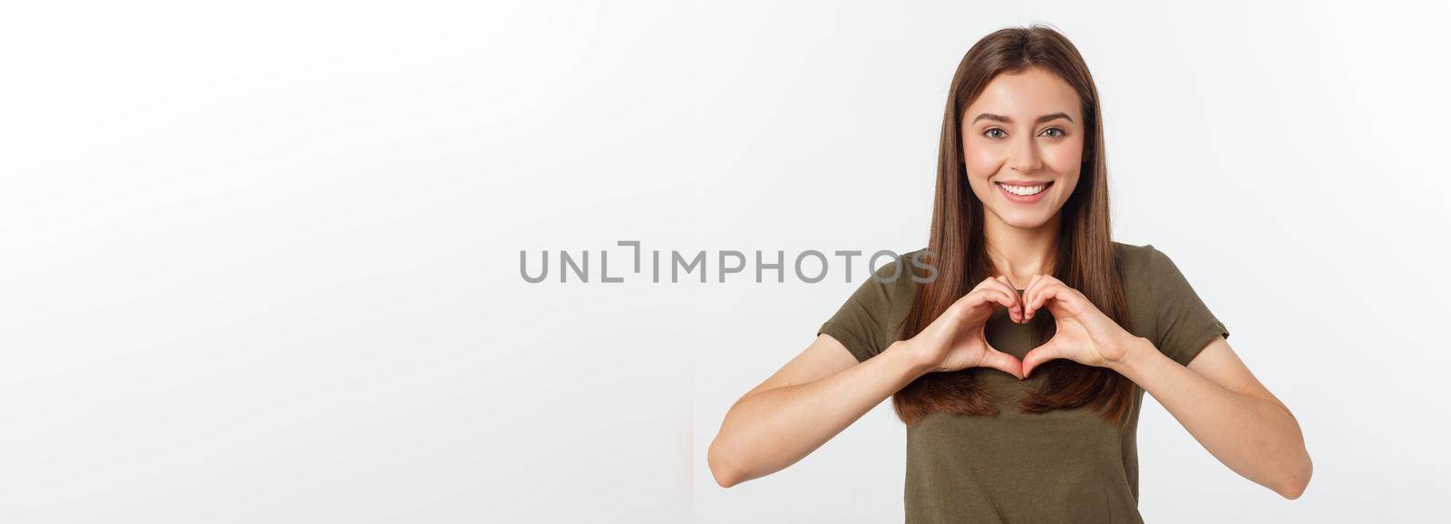 Smiling teenager girl making heart shape with her hands isolated on white