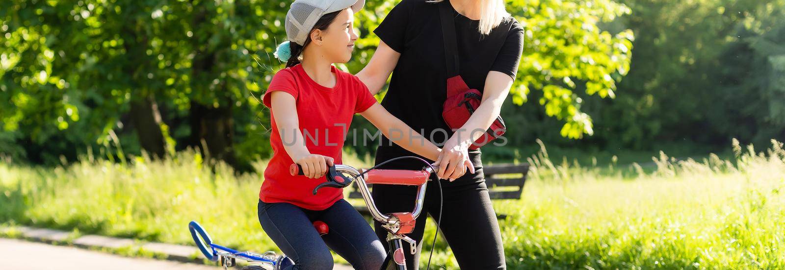 happy little girl with mother practice to riding bicycle.