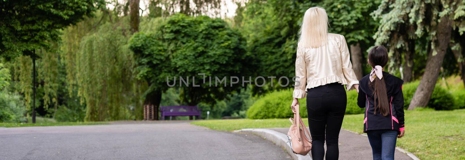 Mother taking daughter to school. Back view