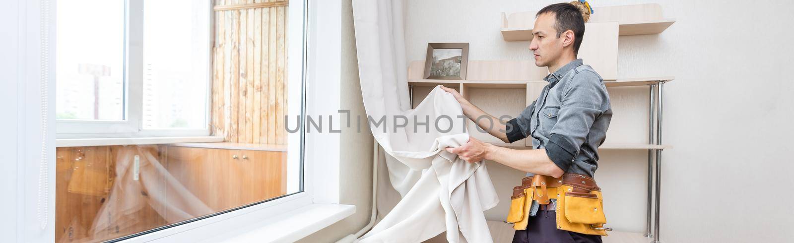 A handyman installing new cornice for curtains, home repair and renovation works by Andelov13