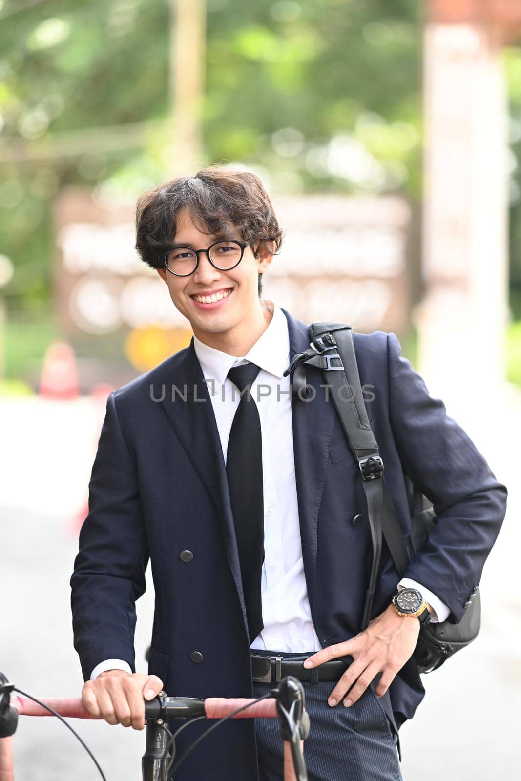 Young businessman walking with his bike in the city street.