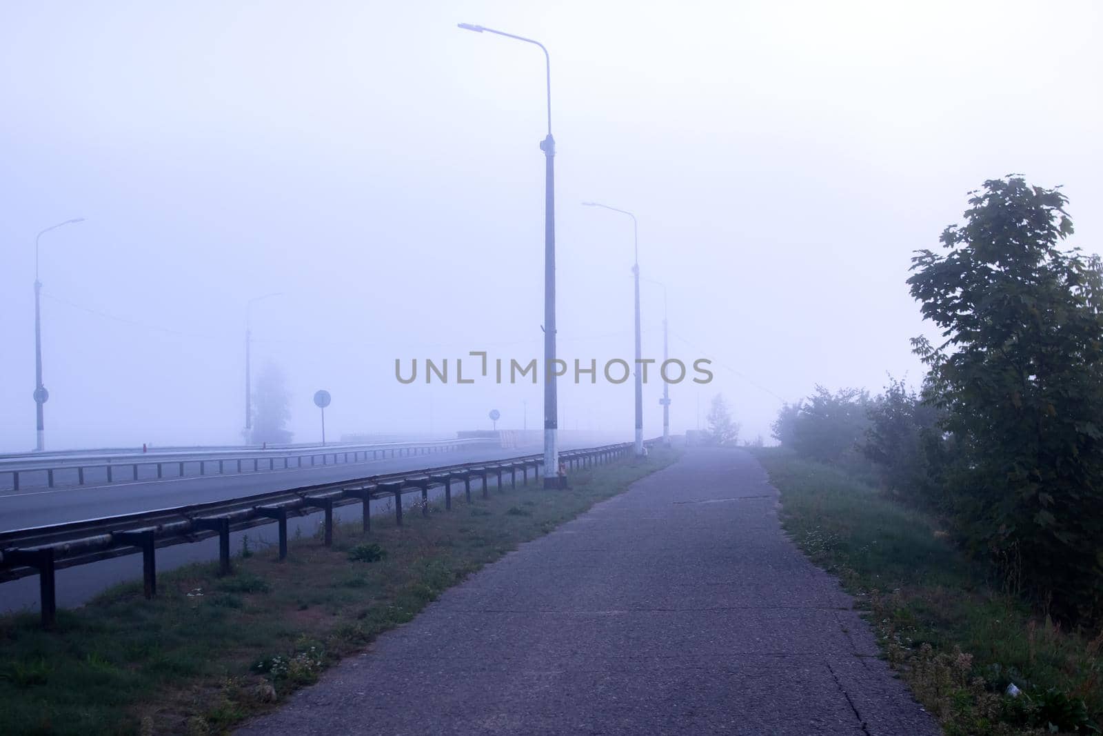 Bridge and road in the fog at dawn close up