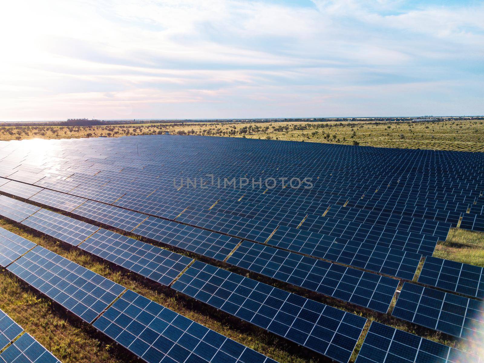 Aerial top view of a solar panels power plant. Photovoltaic solar panels at sunrise and sunset in countryside from above. Modern technology, climate care, earth saving, renewable energy concept