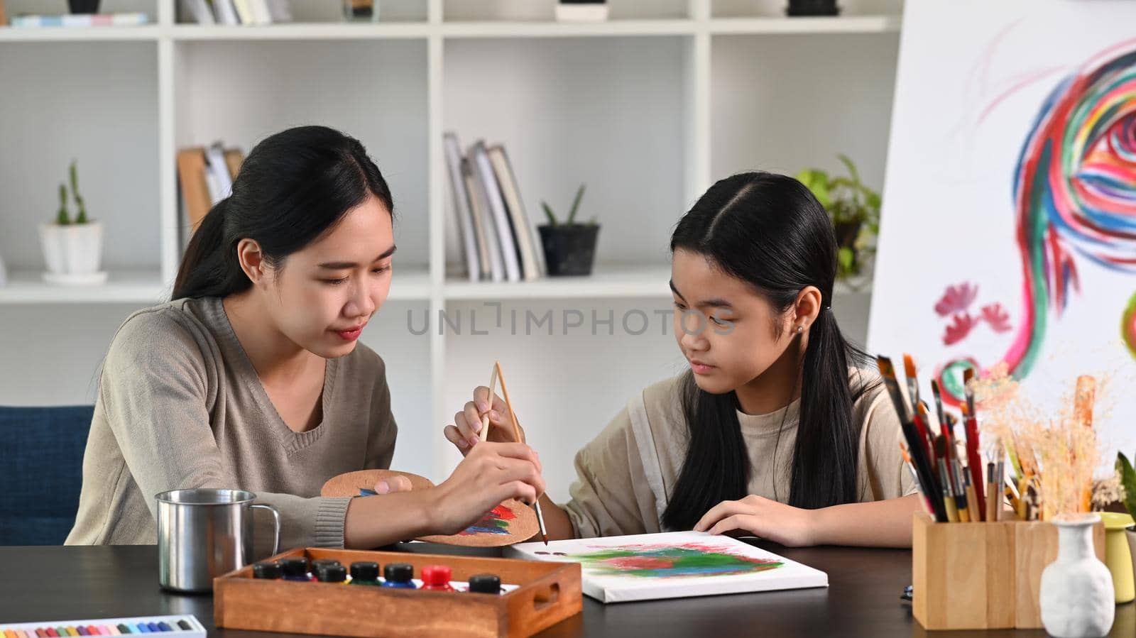 Happy asian girl painting with her mother in living room. by prathanchorruangsak