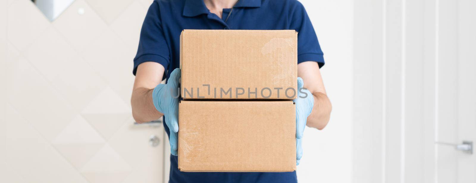 Man from delivery service in t-shirt, in protective mask and gloves giving food order and holding boxes over white background