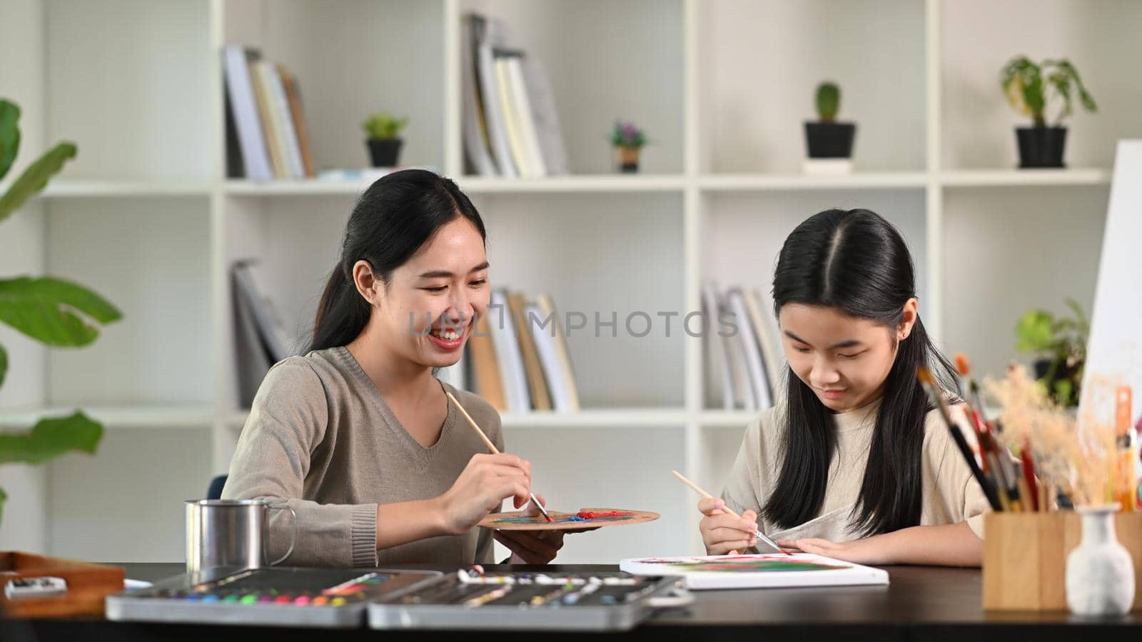 Smiling mother helping her daughter doing creative art homework.